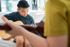 亚洲男孩玩吉他与父亲的生活房间为教学他儿子玩吉他感觉欣赏和鼓励概念快乐家庭学习和有趣的生活方式爱家庭关系