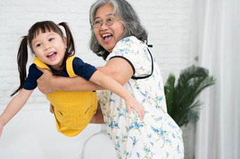 快乐亚洲高级祖母持有和玩与（外）<strong>孙女</strong>的生活房间快乐奶奶穿眼镜和（外）<strong>孙女</strong>拥抱显示爱和哪爱和保护概念