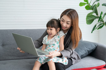 亚洲妈妈。与她的两个孙子有有趣的和玩教育游戏在线与数字电脑移动PC首页的生活房间概念在线教育和有爱心的从父母