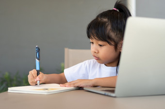 亚洲女孩学生持有笔为采取笔记和做家庭作业和使用的移动PC为在线学习类<strong>首页教育</strong>和距离学习为孩子们在家<strong>教育</strong>概念