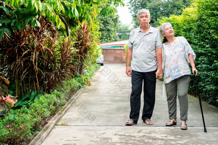 快乐高级夫妇走在一起的花园老上了年纪的使用走坚持帮助走平衡概念爱和哪的家庭和健康保险为家庭