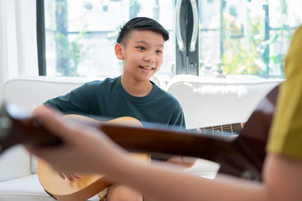 亚洲男孩玩吉他与父亲的生活房间为教学他儿子玩吉他感觉欣赏和鼓励概念快乐家庭学习和有趣的生活方式爱家庭关系