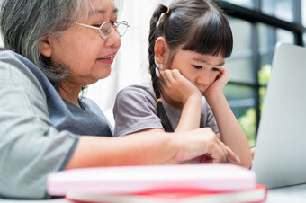 亚洲祖母与她的两个孙子有有趣的和玩<strong>教育</strong>游戏在线与电脑笔记本<strong>首页</strong>的生活房间概念在线<strong>教育</strong>和有爱心的从父母