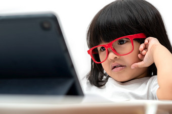小亚洲学龄前儿童女孩穿红色的眼镜和使用平板电脑白色背景亚洲女孩会说话的和学习与视频调用与平板电脑教育概念为学校孩子们