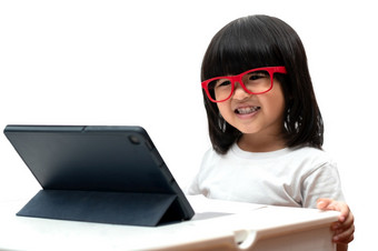 小亚洲学龄前<strong>儿童</strong>女孩穿<strong>红色</strong>的眼镜和使用平板电脑白色背景亚洲女孩会说话的和学习与视频调用与平板电脑教育概念为学校孩子们