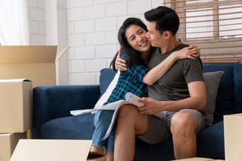 微笑年轻的亚洲快乐夫妇持有蓝图为首页装饰的想法移动一天他们的新首页后购买真正的房地产概念开始新生活为新结婚了夫妇
