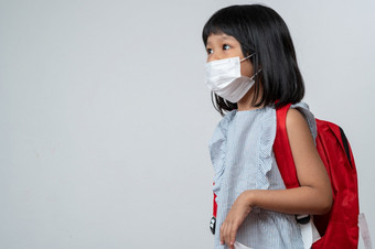 肖像亚洲女孩孩子与保护脸面具和学校背包准备好了为新学校一年与流感大流行限制概念孩子会回来学校和新正常的生活方式