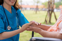 亚洲小心照顾者护士持有的病人手和鼓励的病人轮椅概念快乐退休与哪从照顾者和储蓄和高级健康保险