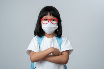 肖像亚洲女孩孩子与保护脸面具和学校背包准备好了为新学校一年与流感大流行限制概念孩子会回来学校和新正常的生活方式