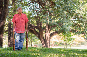 快乐老上了年纪的亚洲男人。使用沃克和走的公园概念快乐退休与哪从照顾者和储蓄和高级健康保险
