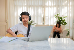 亚洲男孩玩吉他和看在线课程移动PC而练习为学习音乐音乐的仪器在线首页男孩学生研究在线与视频调用老师玩吉他