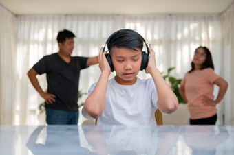 亚洲男孩孩子穿耳机和玩大声音乐不听到争吵而父母有战斗争吵冲突首页不开心问题家庭国内问题的家庭