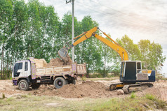 黄色的挖掘机机加载土壤成转储卡车建设网站