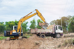 黄色的挖掘机机加载土壤成转储卡车建设网站