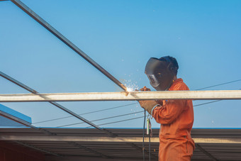 工人焊接橙色工作衣服焊接为屋顶<strong>桁架</strong>