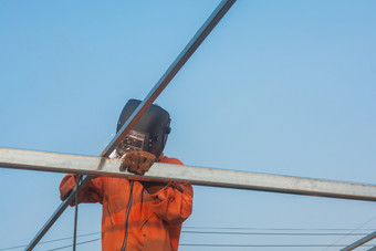 工人焊接橙色工作衣服焊接为屋顶桁架