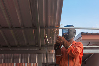 工人焊接橙色工作衣服焊接为屋顶<strong>桁架</strong>