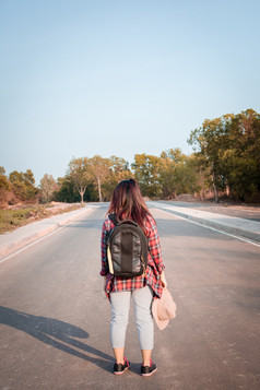 旅行概念旅行女人与背包走沥青路农村