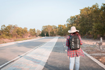 旅行概念旅行女人与背包走沥青路农村