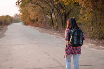 旅行概念旅行女人与背包走沥青路农村