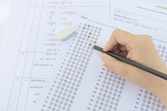 学生手持有铅笔写作选择选择回答表和数学问题表学生测试做检查学校考试