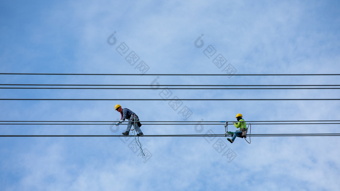 工作人员安装和修改高电压电电缆系统和云天空背景泰国
