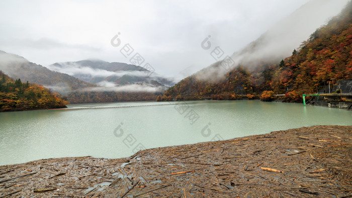 棕色（的）木块浮动前面的大坝和河山雾视图背景秋天季节日本