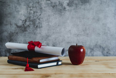 关闭毕业教育季节背景概念附件帽与证书纸书和红色的苹果现代乡村棕色（的）木和灰色水泥毕业大学