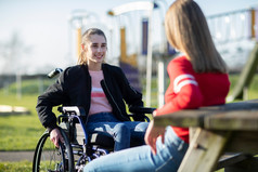 十几岁的女孩轮椅会说话的与朋友公园
