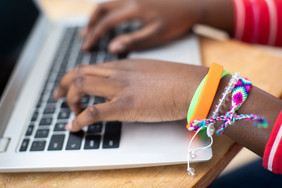 关闭十几岁的女孩穿腕带打字移动电脑键盘