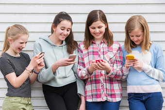 集团年轻的女孩在户外看消息<strong>移动手机</strong>