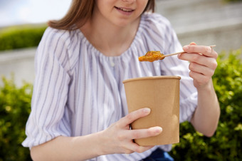 关闭女人吃健康的素食主义者素食者汤外卖午餐从可回收的包装与木勺子