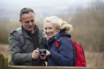 成熟的退休夫妇走秋天冬天农村采取照片数字相机