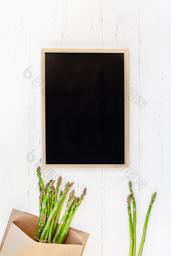有创意的平躺前视图模型新鲜的绿色芦笋与黑板框架白色木表格背景复制空间最小的概念模拟为<strong>餐厅促销</strong>购物出售广告