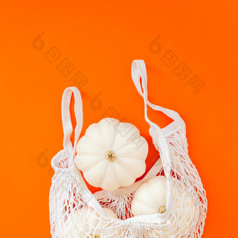 秋天平躺作文与白色南瓜网购物袋大胆的橙色颜色背景有创意的秋天感恩节秋天万圣节概念零浪费风格前视图复制空间