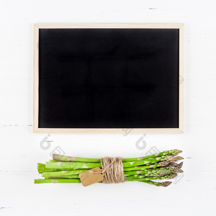 有创意的平躺前视图模型新鲜的绿色芦笋与黑板框架白色木表格背景复制空间最小的概念模拟为餐厅促销购物出售广告