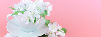 有创意的概念咖啡杯和白色苹果树盛开的花粉红色的背景与明信片模拟和复制空间最小的风格模板为文本