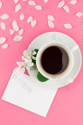 有创意的平躺概念前视图咖啡杯和白色苹果树花花瓣柔和的粉红色的背景与明信片模拟和复制空间最小的风格模板为文本