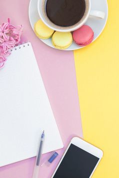 有创意的平躺照片咖啡杯与蛋白杏仁饼和记事本与复制空间粉红色的和黄色的背景最小的风格