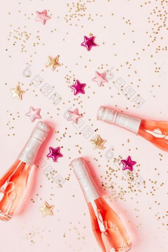 圣诞节新一年作文与瓶玫瑰香槟和金闪亮的闪耀明星五彩纸屑柔和的粉红色的背景前视图庆祝活动平躺聚会，派对有创意的概念