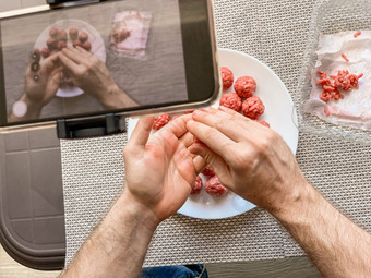 男人。手准备肉丸与生甜馅记录视频智能手机生活方式关闭作文与自然光自制的烹饪视频博客影响者流媒体写博客概念