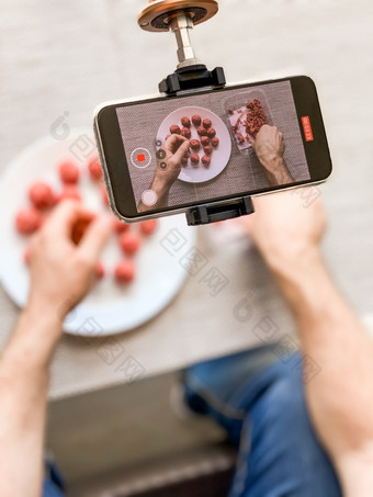 男人。手准备肉丸与生甜馅记录视频智能手机生活方式关闭作文与自然光自制的烹饪视频博客影响者流媒体写博客概念