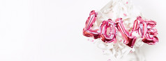 情人节一天有创意的概念充气粉红色的光滑的箔气球词标志爱现在礼物盒子孤立的白色背景前视图平躺与复制空间光和明亮的作文