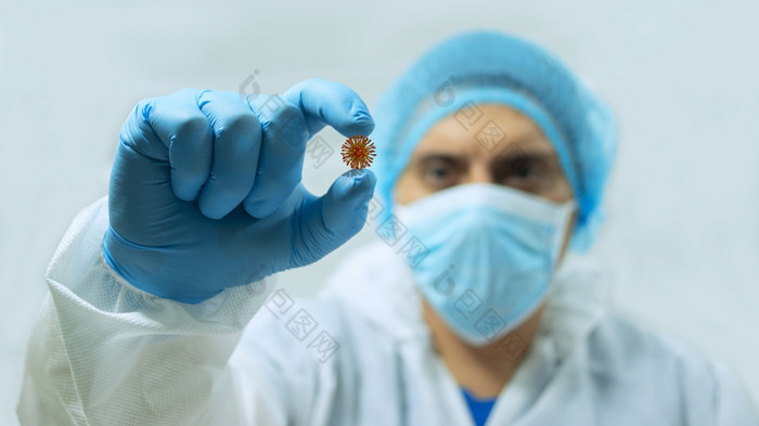 关闭视图医生穿面具和蓝色的手套盯着冠状病毒那持有之间的他的手指与他的手的前景关闭医生穿面具和蓝色的手套盯着病毒那持有之间的他的手指与他的手的前景