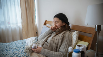 拉美裔女人说谎独自一人她的床上好吧包装生病的与的流感覆盖她的口与她的手而打喷嚏拉美裔女人说谎她的床上好吧包装打喷嚏生病的与的流感