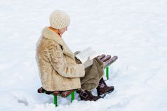 女人坐着板凳上和阅读书冬天雪