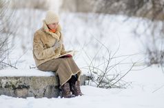 女人坐着板凳上和阅读书冬天雪