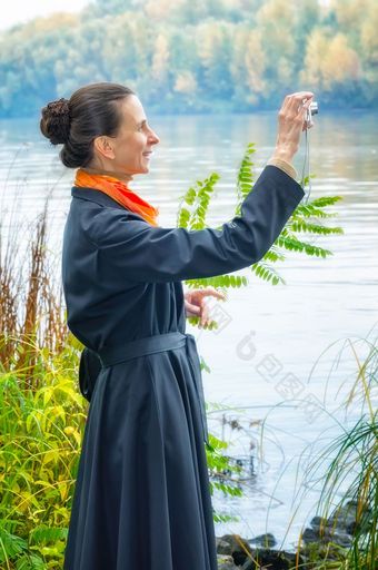 优雅的<strong>高级</strong>业务女人与数字相机袋和橙色围巾采取<strong>图片</strong>沿着的河