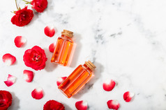 香水玫瑰水玻璃瓶和小红色的玫瑰与花瓣按摩芳香疗法和有机化妆品概念