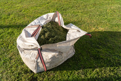 完整的袋与新鲜减少草工作的花园割草的草
